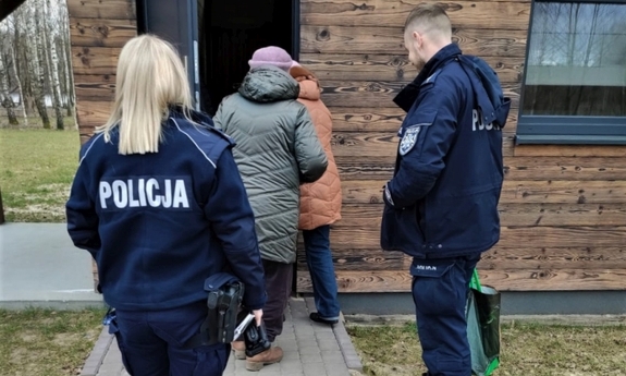 funkcjonariusze pomagają kobietom wnieść dary do domu