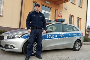 umundurowany policjant stoi przy radiowozie na tle budynku Posterunku Policji w Żytnie