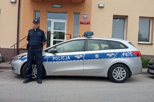 umundurowany policjant stoi przy radiowozie na tle budynku Posterunku Policji w Żytnie