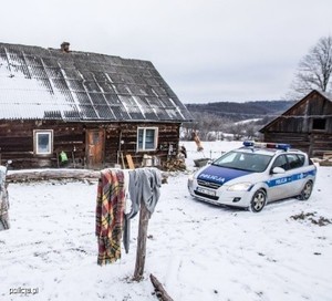 policyjny radiowóz zaparkowany przed budynkiem. Wokół leży śnieg