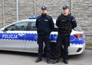 umundurowani policjanci stoją przy radiowozie