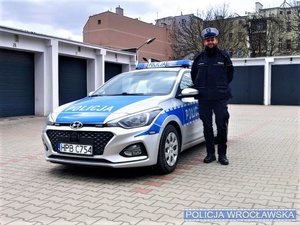 policjant stoi przy radiowozie