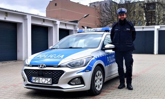 policjant stoi przy radiowozie