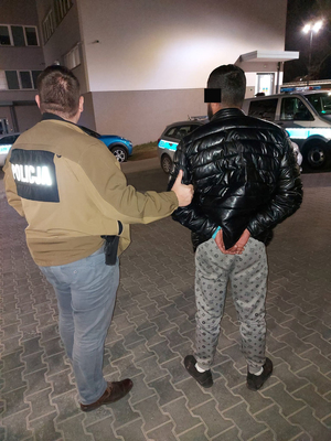 policjant z zatrzymanym mężczyzną w kajdankach