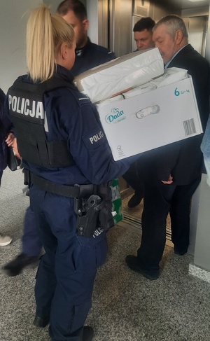 policjanci noszą paczki z darami dla uchodźców