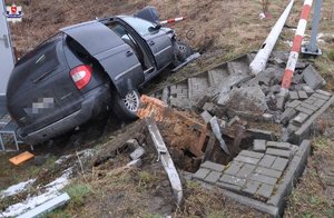 uszkodzony samochód marki Chrysler, uszkodzone elementy infrastruktury drogowo-kolejowej