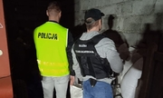 policjant i funkcjonariusz służby celno-skarbowej stoją przy zabezpieczonych workach z nielegalnym tytoniem