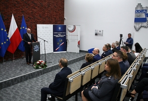 uczestnicy konferencji słuchają przemówienia prelegenta stojącego przy mównicy