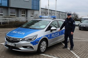 policjant stoi przy radiowozie