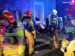 &quot;Na zdjęciu widoczni strażacy przez zadymionym budynkiem mieszkalnym, w którym wybuchł pożar