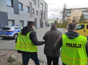 dwaj policjanci prowadzą zatrzymanego mężczyznę