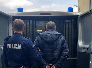 policjant z zatrzymanym mężczyzną przy radiowozie