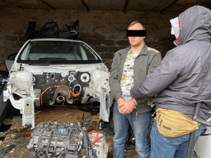 wrak pojazdu i policjant z zatrzymanym mężczyzną