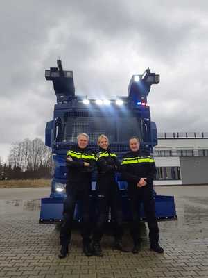 troje niderlandzkich policjantów pozuje do zdjęcia na tle specjalnego pojazdu policyjnego