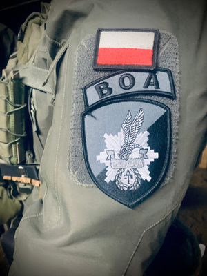 Ramię umundurowanego funkcjonariusza BOA z naszywką logo BOA i flagą Polski.