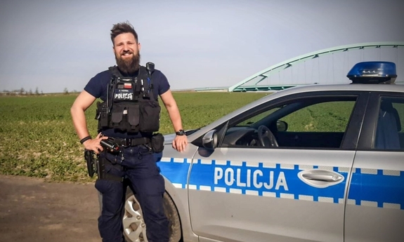 policjant stoi przy radiowozie