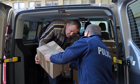 Policjant oraz osoba cywilna pakująca pudełka do samochodu