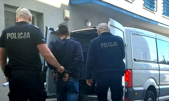 dwaj policjanci prowadza mężczyznę do radiowozu