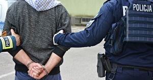 policjanci trzymają zatrzymanego mężczyznę w kajdankach