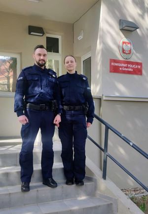 policjant i policjantka przed budynkiem komisariatu