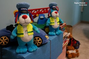 Policyjne maskotki Sznupek stoją na stosie prezentów