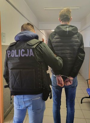 policjant z zatrzymanym mężczyzną w kajdankach