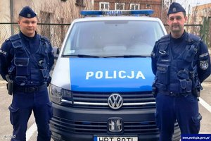 dwaj umundurowani policjanci przed radiowozem