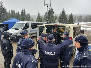 Grupa policjantów stojąca przy radiowozie