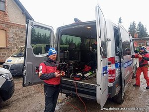 Policjanci wraz z ratownikiem opatrują nogę poszkodowanej