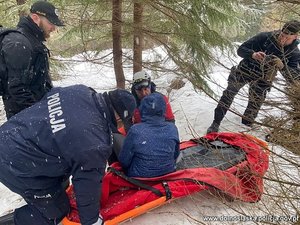 Poszkodowana na desce do transportu medycznego której pomagają policjanci i ratownicy