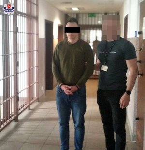 policjant z zatrzymanym mężczyzną w kajdankach