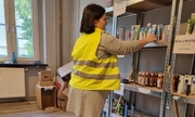 kobieta w odblaskowej kamizelce ustawia towary na półkach