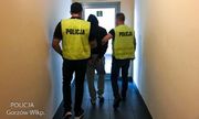 Dwaj policjanci w żółtych kamizelkach z napisem Policja prowadzą zatrzymanego