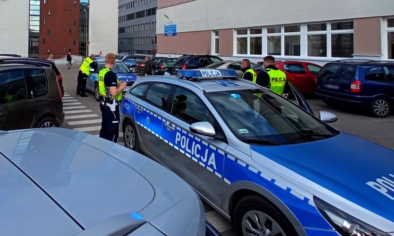 policjanci stoją przy radiowozie