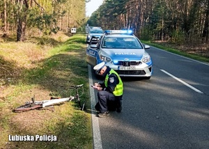 Policjant wykonuje oględziny w miejscu wypadku drogowego