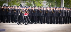 poczet sztandarowy niesie złożoną flagę, z tyłu widoczne są pododdziały funkcjonariuszy straży pożarnej