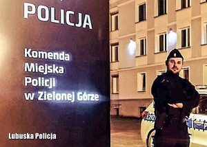 Umundurowany policjant stojący przy banerze