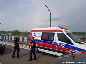 policjanci na miejscu interwencji, na drodze stoi karetka pogotowia