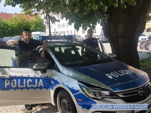 dwóch policjantów stojących przy radiowozie