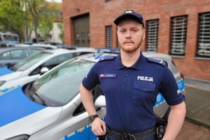 umundurowany policjant stoi przy radiowozie