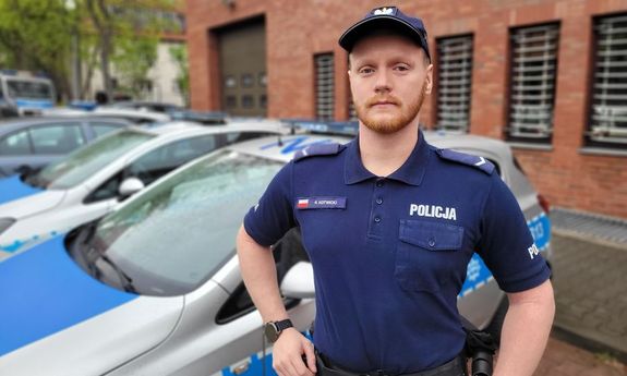 umundurowany policjant stoi przy radiowozie