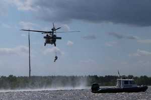 Black Hawk wraz z opuszczanym na linach ratownikiem oraz łódź policyjna na wodach Zalewu Zegrzyńskiego