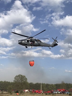 lecący policyjny śmigłowiec z podczepionym zbiornikiem na wodę typu „Bambi Bucket”