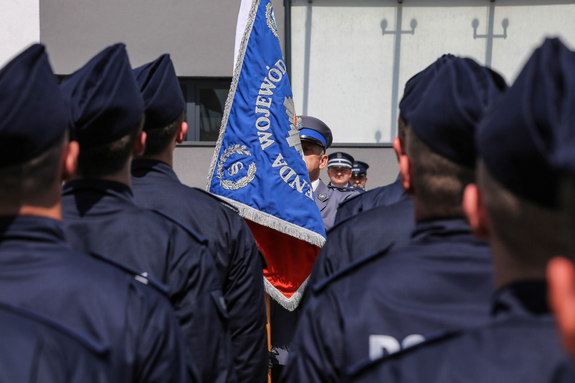 nowo przyjęci policjanci stojący tyłem podczas uroczystego ślubowania