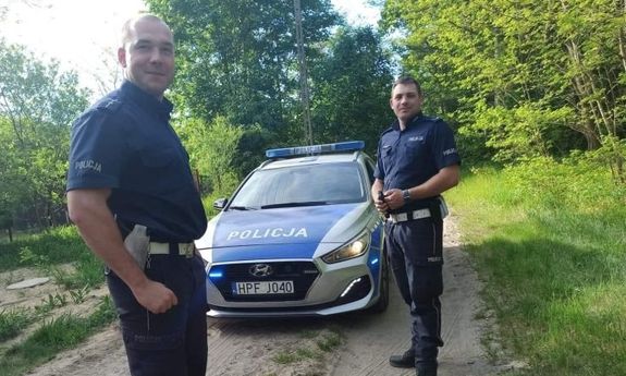 dwaj policjanci stoją przy radiowozie