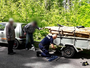 Policjant wymienia koło w przyczepce seniorów