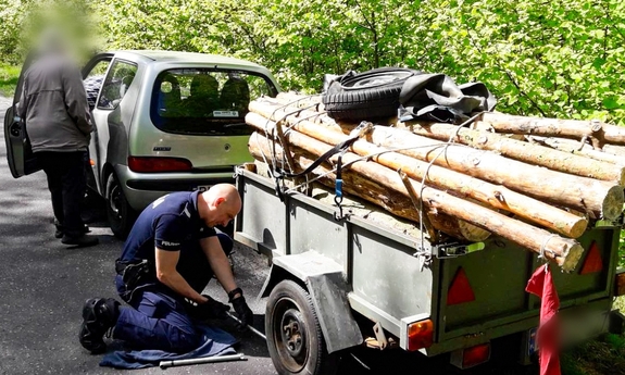 Policjant wymienia koło w przyczepce seniorów