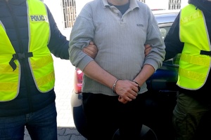 dwóch policjantów prowadzi zatrzymanego mężczyznę