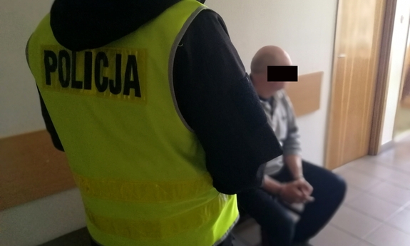 dwóch policjantów prowadzi zatrzymanego mężczyznę