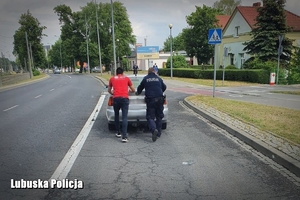 policjant i mężczyzna pchają samochód